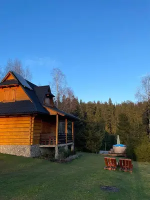 a log cabin with picnic tables and a fountain at Gorczańska Ostoja in Klikuszowa