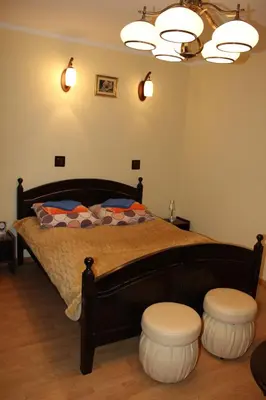 a bedroom with a large bed with two stools at Dom Pielgrzyma in Kalwaria Zebrzydowska