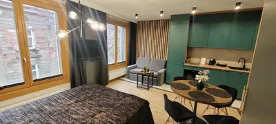 a bedroom with a bed and a table and a kitchen at Apartamenty Kossak Residence in Kraków