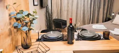 a table with a bottle of wine and plates and glasses at Apartamenty Kossak Residence in Kraków