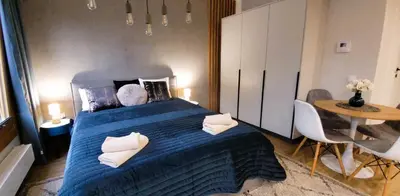 a bedroom with a blue bed and a table at Apartamenty Kossak Residence in Kraków