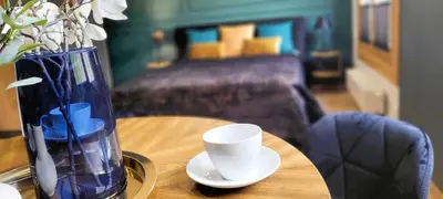 a table with a vase and a cup on it at Apartamenty Kossak Residence in Kraków
