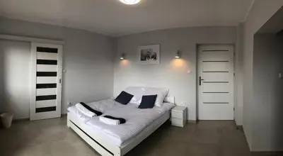 a bedroom with a bed with white sheets and blue pillows at Noclegi Bachowice - Zator Energylandia Wadowice in Bachowice