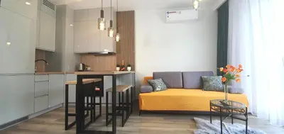 a living room with a couch and a kitchen at Apartament Green Diamond Rakowicka in Kraków