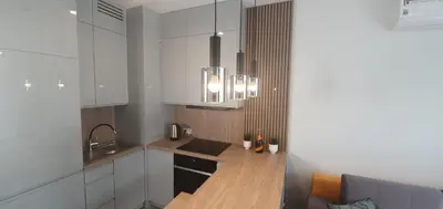 a kitchen with white cabinets and a wooden counter top at Apartament Green Diamond Rakowicka in Kraków