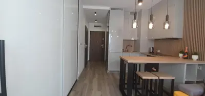 a kitchen with white cabinets and a wooden counter top at Apartament Green Diamond Rakowicka in Kraków
