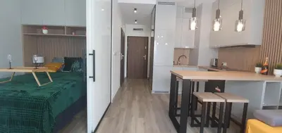 a kitchen and a living room with a table at Apartament Green Diamond Rakowicka in Kraków