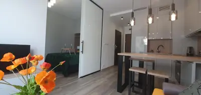 a kitchen and living room with orange flowers on a table at Apartament Green Diamond Rakowicka in Kraków