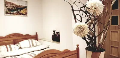 a bedroom with a vase with white flowers in it at NOCLEGI POD STODOŁĄ in Kraków