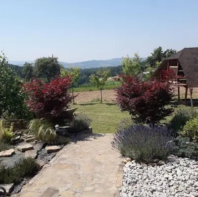 a garden with rocks and trees and a house at Dom w okolicach Czchowa in Wytrzyszczka