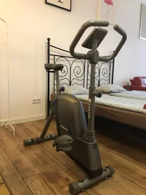 a exercise bike on the floor next to a bed at Apart 3b in Kraków