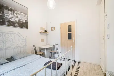 a white bedroom with a bed and a table at Laykonik in Kraków