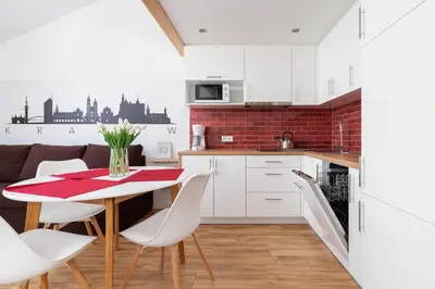 a kitchen with white cabinets and a table and chairs at Duplex Apartment Brandy Cracow by Noclegi Renters in Kraków
