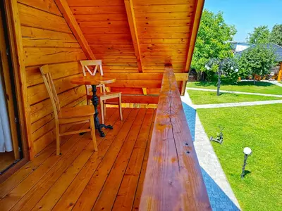 a porch of a wooden cabin with a table and a chair at Chatki U Hanusi in Czchów