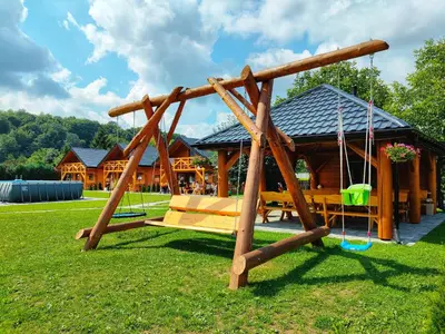 a wooden swing set in front of a cabin at Chatki U Hanusi in Czchów