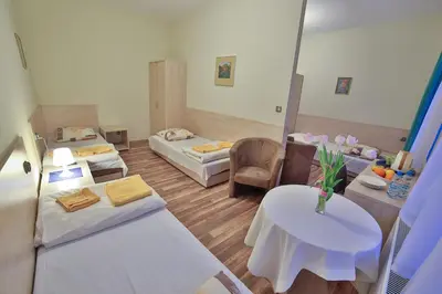 a room with two beds and a table and chairs at Parkowy Dworek in Rabka