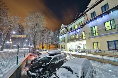 a parking lot with snow covered cars in front of a building at Parkowy Dworek in Rabka