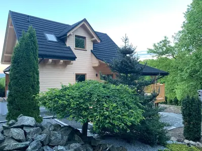 a house with a black roof and a rock garden at Dom na Leśnej in Po”łwieś