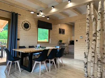 a dining room with a wooden table and chairs at Dom na Leśnej in Po”łwieś