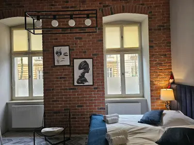 a bedroom with a brick wall with a bed and windows at JUWEL Uroczy Apartament 2A Stare Miasto Kraków in Kraków