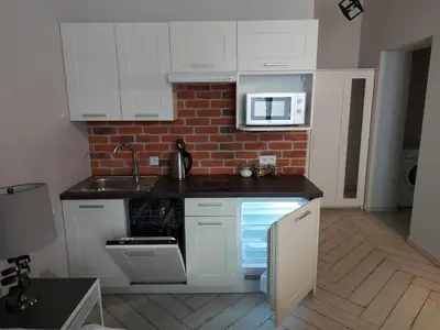 a kitchen with white cabinets and a brick wall at JUWEL Uroczy Apartament 2B Stare Miasto Kraków in Kraków