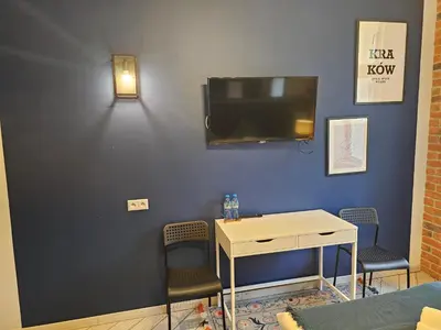 a room with a table and chairs and a tv on a wall at JUWEL Uroczy Apartament 2B Stare Miasto Kraków in Kraków