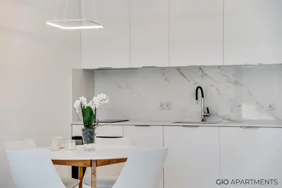 a white kitchen with a vase of flowers on a table at Old Town - Rajska Signature Suites by Gio Loft in Kraków