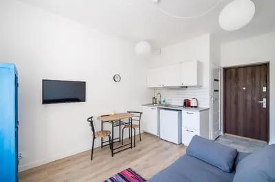 a living room with a blue couch and a kitchen at Mickiewicza Old Town Apartment WAWELOFTS in Kraków