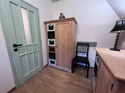 a room with a cabinet and a chair next to a door at Retro Domek - Domek z ogrodem w górach in Sułkowice