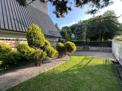 a garden with bushes and a house at Retro Domek - Domek z ogrodem w górach in Sułkowice