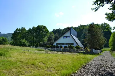 a barn on a hill with a gravel road in front at Retro Domek - Domek z ogrodem w górach in Sułkowice