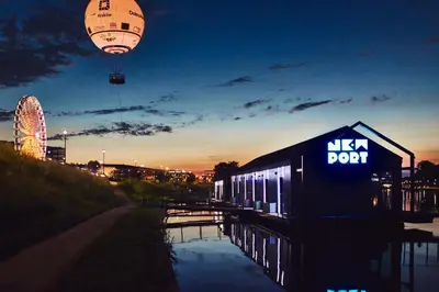 a train is parked next to a river with a city at New Port Aparthotel in Kraków