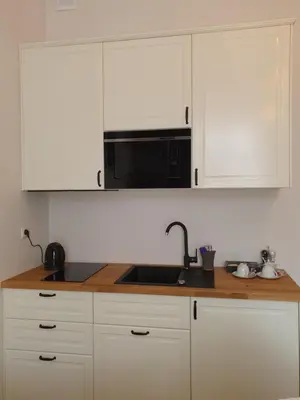 a kitchen with white cabinets and a black microwave at Historic Old Town Kazimierz in Kraków