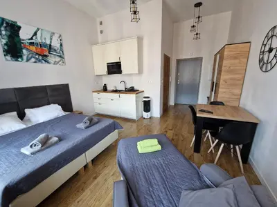 a bedroom with two beds and a desk and a kitchen at Historic Old Town Kazimierz in Kraków