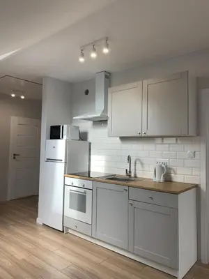 a kitchen with white cabinets and a white refrigerator at Hostel Pokoje 15G in Skawina
