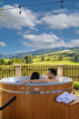 a man and a woman sitting in a hot tub at Villa Gorczański Zakątek Agroturystyka in Konina
