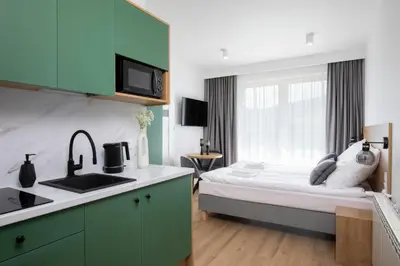 a bedroom with a bed and a kitchen with a sink at Villa Gorczański Zakątek Agroturystyka in Konina