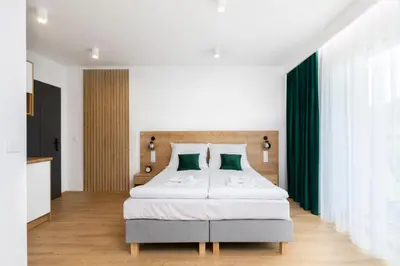 a bedroom with a bed with white sheets and green pillows at Villa Gorczański Zakątek Agroturystyka in Konina