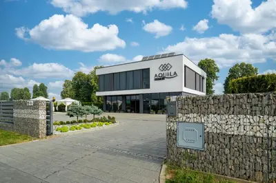 a building with a stone fence in front of it at Aquila Hotel in Zator