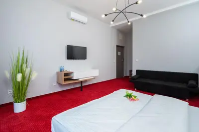 a living room with a white bed and a black couch at Aquila Hotel in Zator