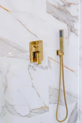 a bathroom with a gold shower head on a wall at Aquila Hotel in Zator