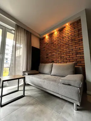 a living room with a couch and a brick wall at Apartament na Rydlówce in Kraków