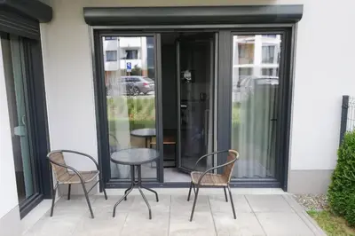 a patio with two chairs and a table in front of a building at Apartament na Rydlówce in Kraków