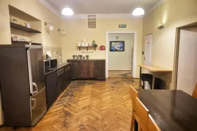 a large kitchen with wooden floors and a refrigerator at 50 People Apartment in Kraków
