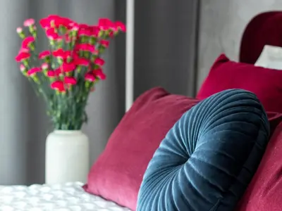 a vase filled with red flowers next to red pillows at Golden Star Apartment in Kraków