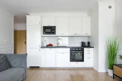 a kitchen with white cabinets and a couch in a living room at Golden Star Apartment in Kraków