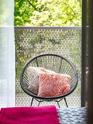 a black chair with two pink pillows on a balcony at Golden Star Apartment in Kraków