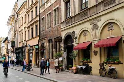 a group of people walking down a street with buildings at Mikolajska Residence in Kraków