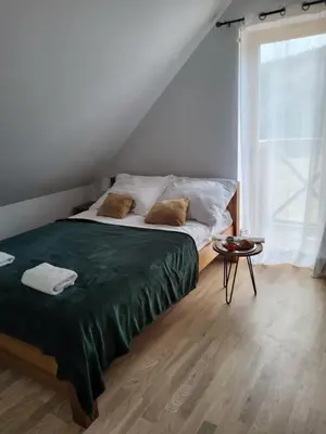 a bedroom with a bed with a green blanket and a window at Willa Białego Wilka w Zawoi in Zawoja