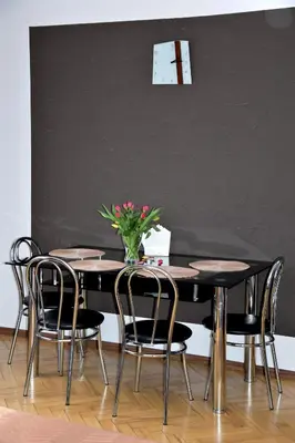 a table with chairs and a vase with flowers on it at Travel Apartament Cracow in Kraków